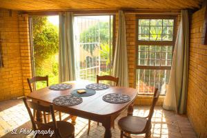 a dining room table with chairs and a large window at 14 Penguin Place, Melkbosstrand in Melkbosstrand