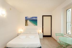 a white bedroom with a bed and a table at San Teodoro - Civico 35 in San Teodoro