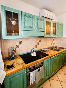 uma cozinha com armários verdes e um lavatório em casa a pochi minuti dalla spiaggia di vignola em Vignola Mare