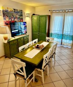 uma sala de jantar com uma mesa e cadeiras e uma televisão em casa a pochi minuti dalla spiaggia di vignola em Vignola Mare
