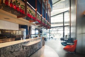a restaurant with a bar with red chairs at Lumen Bangkok Udomsuk Station in Bangkok