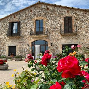 um edifício de pedra com flores em frente em Can Mas em Sant Pere Pescador