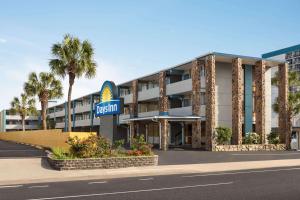 an exterior view of a hotel with a hotel sign and palm trees at Days Inn by Wyndham Myrtle Beach-Beach Front in Myrtle Beach