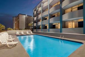 um hotel com piscina e cadeiras e um edifício em Days Inn by Wyndham Myrtle Beach-Beach Front em Myrtle Beach