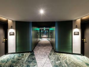 un couloir avec ascenseurs dans un bâtiment aux murs verts dans l'établissement Novotel Lisboa, à Lisbonne