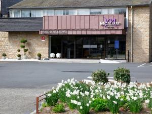 a store with white flowers in front of a street at Mercure Mont Saint Michel in Le Mont Saint Michel