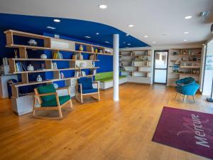 een bibliotheek met blauwe muren en stoelen en boekenplanken bij Mercure Mont Saint Michel in Le Mont Saint Michel