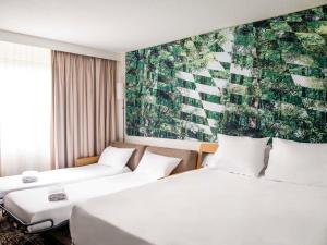 - 2 lits dans une chambre d'hôtel ornée d'une peinture murale dans l'établissement Novotel Bordeaux Mérignac, à Mérignac
