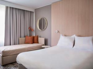 Habitación de hotel con cama y sofá en Novotel Bordeaux Mérignac en Mérignac
