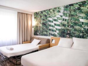 una habitación de hotel con 2 camas y un cuadro en la pared en Novotel Bordeaux Mérignac en Mérignac