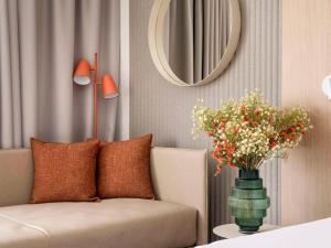 uma sala de estar com um sofá e um vaso com flores em Novotel Bordeaux Mérignac em Mérignac