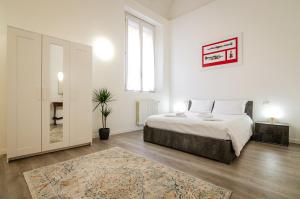 a white bedroom with a bed and a rug at San Giorgio Loft in Bologna