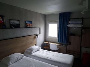 a hotel room with two beds and a desk and a window at ibis Bayonne Centre in Bayonne