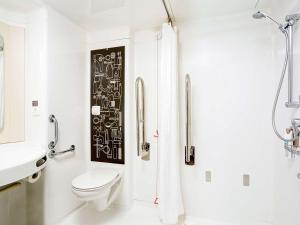 ein weißes Bad mit einem WC und einer Dusche in der Unterkunft ibis London City - Shoreditch in London