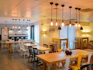 un restaurante con mesas de madera, sillas y luces en Novotel Suites Rouen Normandie, en Rouen