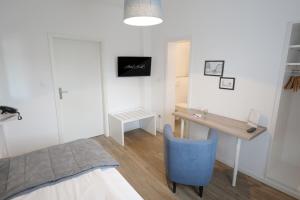 1 dormitorio con escritorio y silla azul en Hotel Kühl en Neumünster