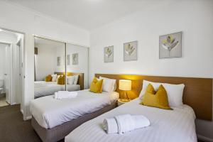 a bedroom with two beds with yellow pillows at Northbridge Hideaway 2BDR 1BTH in Perth