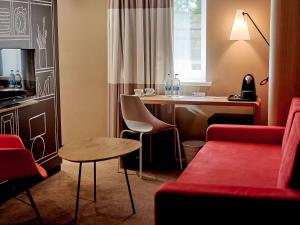 um quarto de hotel com um sofá vermelho e uma secretária em ibis Irkutsk Center em Irkutsk