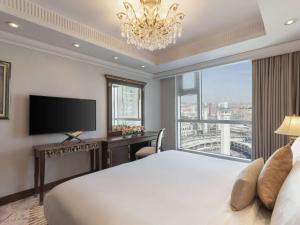 a bedroom with a large bed and a large window at Raffles Makkah Palace in Mecca