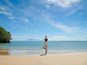 une personne fait du yoga sur la plage dans l'établissement Raffles Bali, à Jimbaran