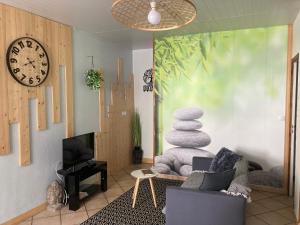 uma sala de estar com um relógio e uma cadeira e uma televisão em Sélénite, Chaleureuse & cocooning em Bogny Sur Meuse