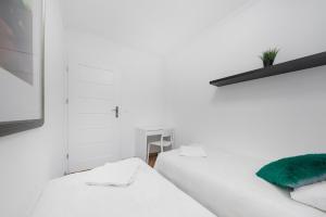 dwa łóżka w pokoju z białymi ścianami w obiekcie MGR Pokoje w samym Centrum Warszawy by Metro Rondo ONZ - SUPER Bed Year23 w Warszawie