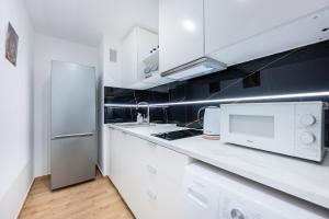 kuchnia z białymi szafkami i lodówką w obiekcie MGR Pokoje w samym Centrum Warszawy by Metro Rondo ONZ - SUPER Bed Year23 w Warszawie +1 zdjęcie