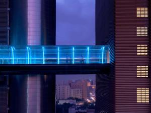 La Cigale Hotel Managed by Accor في الدوحة: وجود جسر ازرق في وسط المدينة في الليل