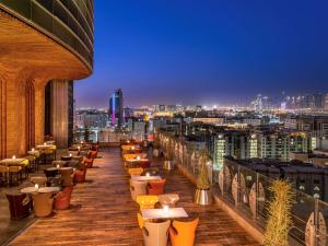 eine Bar auf dem Dach mit Tischen und Stühlen auf einem Gebäude in der Unterkunft La Cigale Hotel Managed by Accor in Doha