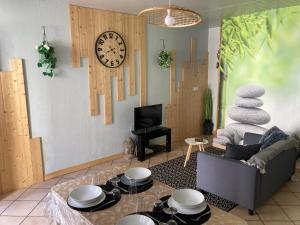 uma sala de estar com uma mesa e um relógio na parede em Sélénite, Chaleureuse & cocooning em Bogny Sur Meuse