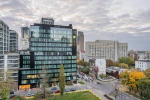 wysoki szklany budynek w środku miasta w obiekcie MGR Pokoje w samym Centrum Warszawy by Metro Rondo ONZ - SUPER Bed Year23 w Warszawie