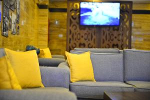 sala de estar con sofás con almohadas amarillas y TV en Petra Corner Hotel en Wadi Musa