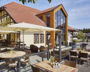 un patio al aire libre con mesas y sillas y un edificio en Lindner Hotel Nurburgring Motorsport, part of JdV by Hyatt en Nürburg