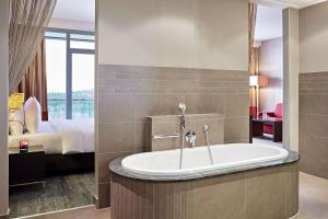 ein Badezimmer mit einer Badewanne und ein Schlafzimmer mit einem Bett in der Unterkunft Lindner Hotel Nurburgring Congress, part of JdV by Hyatt in Nürburg
