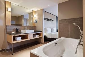 ein Bad mit einer Badewanne, einem Waschbecken und einem Bett in der Unterkunft Lindner Hotel Nurburgring Congress, part of JdV by Hyatt in Nürburg