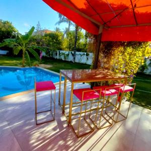 Qaryat ShākūshにあるTwo pools four bedrooms private villaのスイミングプールの隣のパラソルの下にテーブルと椅子
