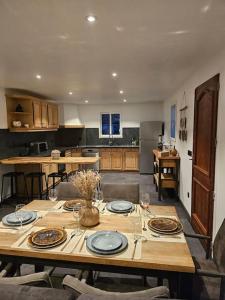 a kitchen with a wooden table with plates and wine glasses at Superbe bas de Villa au calme in Cagnes-sur-Mer