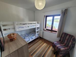 ein Schlafzimmer mit Etagenbetten, einem Stuhl und einem Fenster in der Unterkunft Duplex con Vistas a la Ria in Miengo