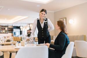 Dos mujeres sentadas en una mesa en un restaurante en Hotel-Residence Klosterpforte en Marienfeld