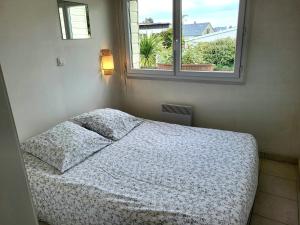 una cama en una habitación con ventana en La Maison du Rivage, en Bretteville-sur-Ay