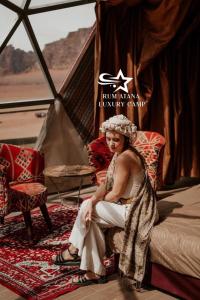 a woman sitting on a bed in a tent at RUM ATANA lUXURY CAMP in Wadi Rum