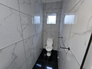 a white bathroom with a toilet and a window at Freedommedia guesthouse in Gqeberha