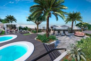 un patio con piscina y palmeras en Hotel LIVVO Anamar Suites, en Playa del Inglés