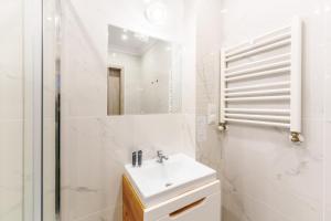 a white bathroom with a sink and a shower at Nadmorski Apartament I by Holiday&Sun in Grzybowo