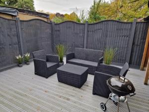 a patio with wicker chairs and a grill on a deck at New! Lovely 2 Bed Serviced Apartment with free parking in London