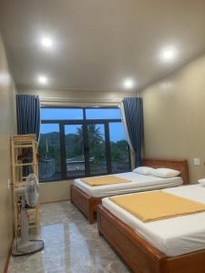 a bedroom with two beds and a large window at Cat Ba Rustic Homestay in Cat Ba