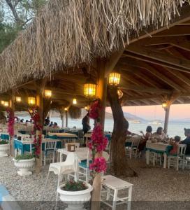 ein Restaurant am Strand mit Tischen und Stühlen in der Unterkunft KIYI SUITES Otel in Yakaköy