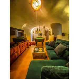 Cueva Ventica في Benamaurel: غرفة معيشة مع أريكة خضراء وطاولة بلياردو