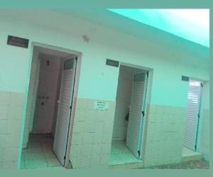 a bathroom with three stalls in a room with doors at Hostal Las Carretas in San Miguel de Tucumán