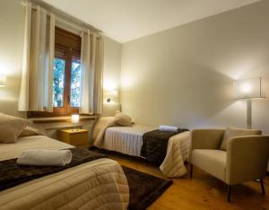 a bedroom with two beds and a chair and a window at Petit Castanyer in Viladrau